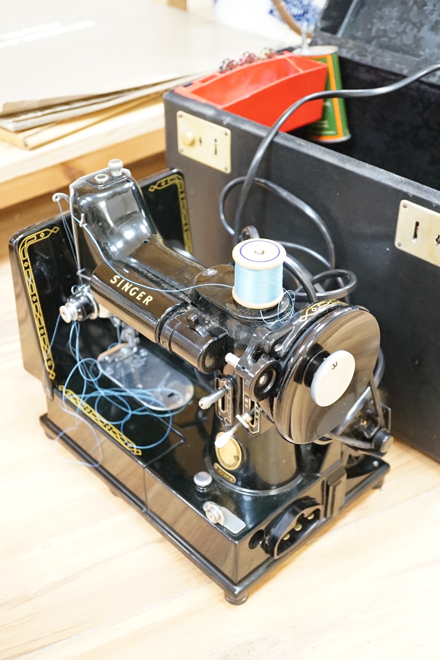 A cased portable Singer Featherweight 222K sewing machine with accessories
